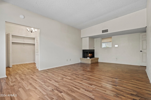 unfurnished living room with a textured ceiling, light hardwood / wood-style flooring, and a notable chandelier