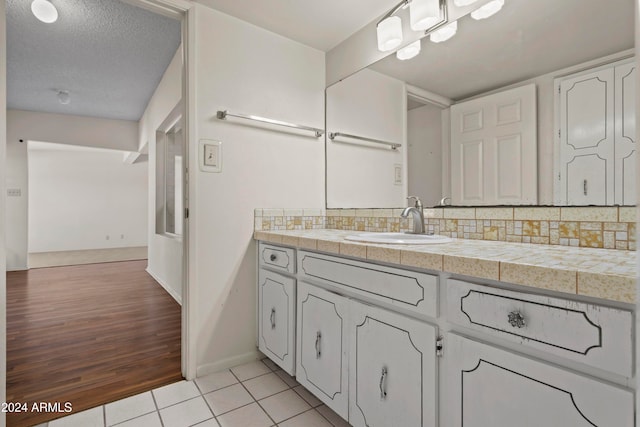 bathroom featuring decorative backsplash, vanity, a textured ceiling, and hardwood / wood-style flooring