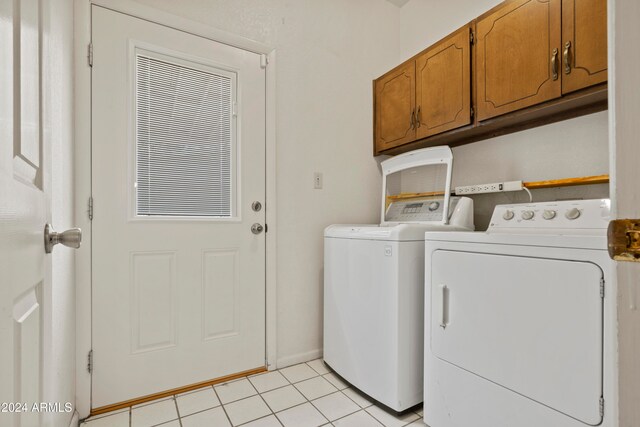 clothes washing area featuring cabinets, independent washer and dryer, and light tile patterned floors