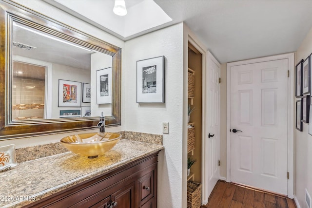 bathroom with vanity, hardwood / wood-style floors, and a skylight