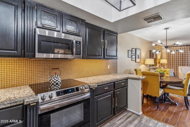 kitchen featuring light stone counters, decorative backsplash, stainless steel appliances, and light hardwood / wood-style flooring