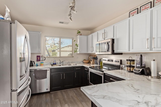 kitchen with sink, white cabinets, dark hardwood / wood-style flooring, light stone counters, and stainless steel appliances