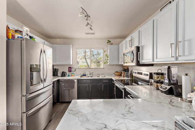 kitchen featuring appliances with stainless steel finishes, light stone countertops, sink, and white cabinets