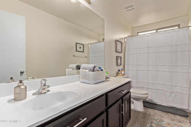 bathroom with hardwood / wood-style flooring, vanity, a shower with shower curtain, and toilet