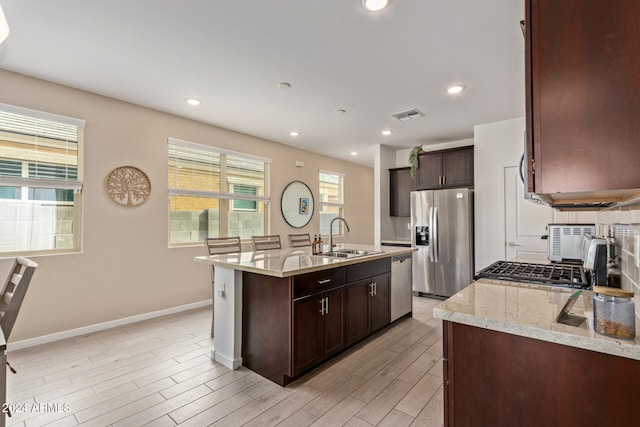 kitchen with a wealth of natural light, sink, stainless steel appliances, and a center island with sink