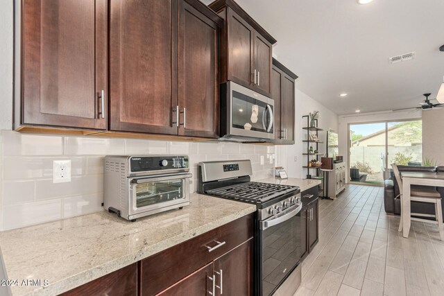 kitchen featuring light stone countertops, appliances with stainless steel finishes, light wood-type flooring, decorative backsplash, and ceiling fan