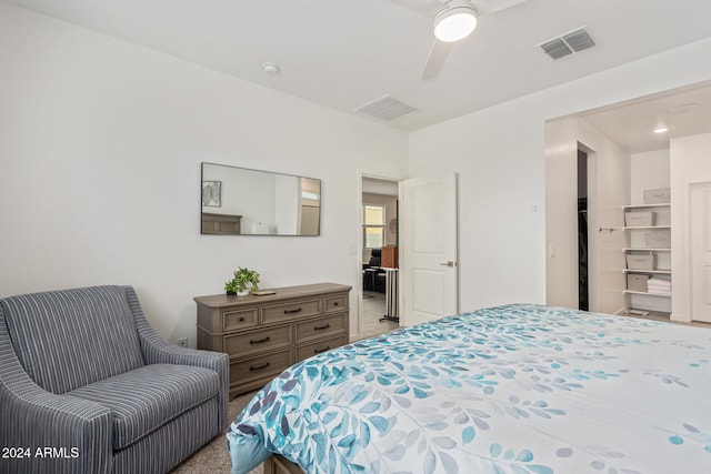 carpeted bedroom with ceiling fan and a spacious closet