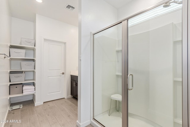 bathroom with vanity, hardwood / wood-style flooring, and a shower with door