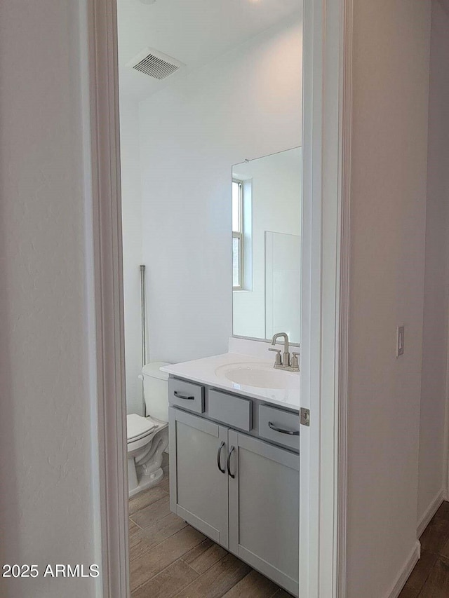 bathroom with hardwood / wood-style floors, vanity, and toilet