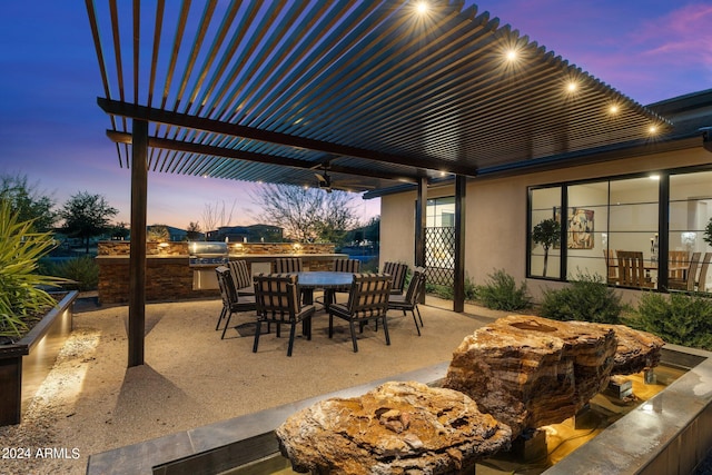 patio terrace at dusk with a pergola and area for grilling