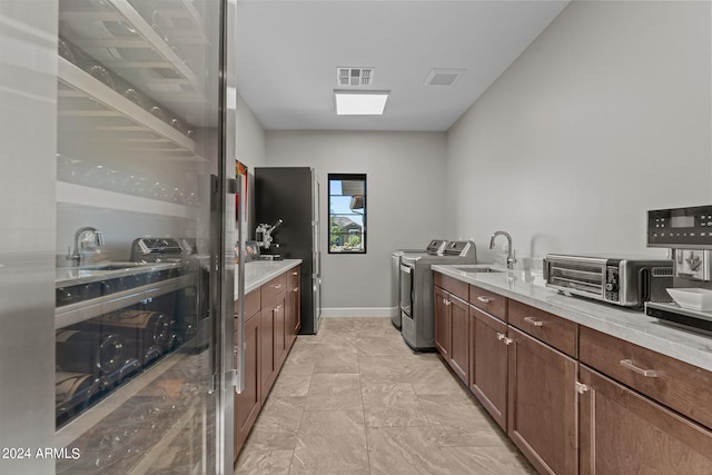 kitchen featuring separate washer and dryer, light stone counters, and sink