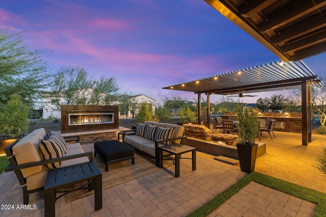 patio terrace at dusk featuring an outdoor living space with a fireplace and a pergola