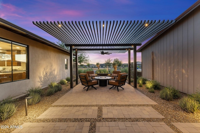 patio terrace at dusk with a pergola, ceiling fan, and an outdoor fire pit