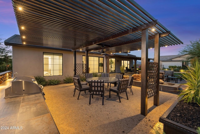 patio terrace at dusk with ceiling fan, area for grilling, a pergola, and grilling area