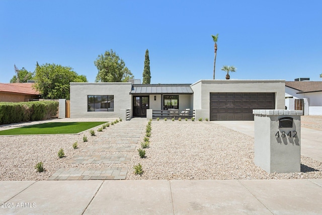 4842 E Surrey Ave, Scottsdale, AZ 85254 - contemporary house featuring an attached garage, concrete driveway, stucco siding, a standing seam roof, and a metal roof