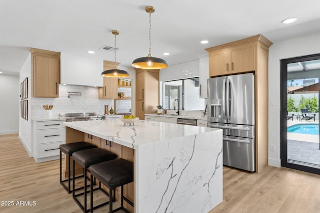 4842 E Surrey Ave, Scottsdale, AZ 85254 - kitchen featuring appliances with stainless steel finishes, light wood-style flooring, backsplash, a kitchen island, and light brown cabinets