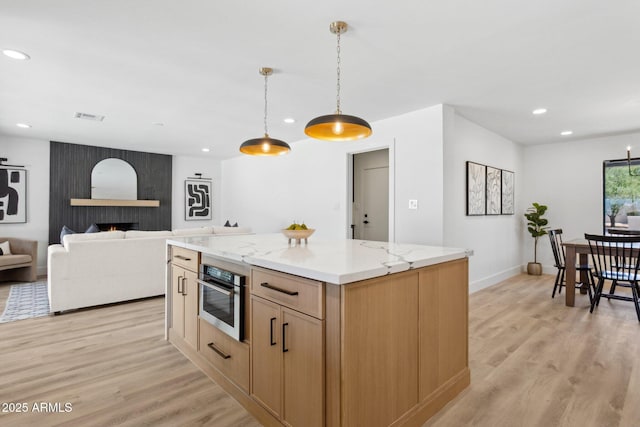 4842 E Surrey Ave, Scottsdale, AZ 85254 - kitchen featuring recessed lighting, light wood-style floors, decorative light fixtures, a kitchen island, and light stone counters