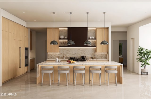 kitchen featuring light brown cabinets, an island with sink, pendant lighting, and light stone counters