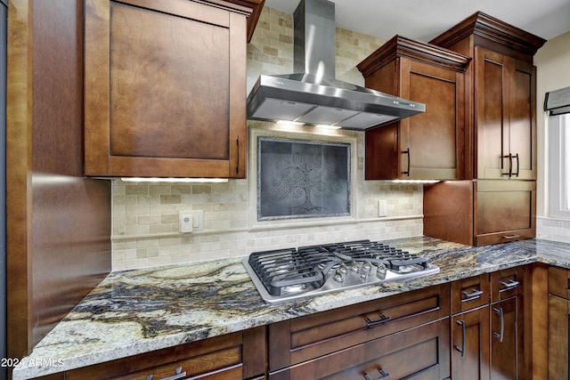 kitchen with tasteful backsplash, wall chimney exhaust hood, stone counters, and stainless steel gas cooktop