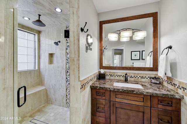 bathroom with backsplash, vanity, tiled shower, and tile walls