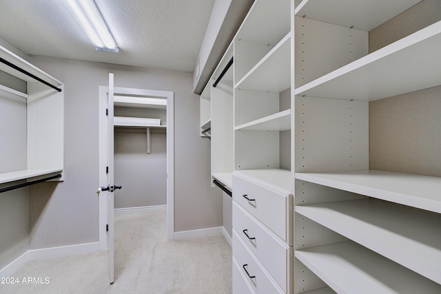 walk in closet with light carpet