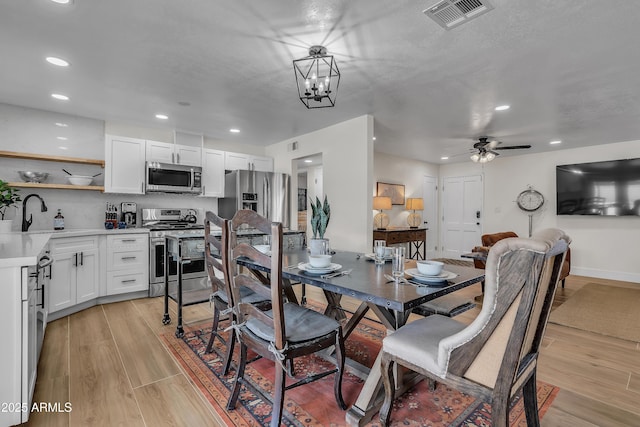 dining room with sink, ceiling fan with notable chandelier, and a textured ceiling