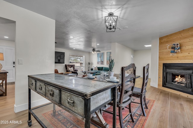 dining room with a chandelier, light hardwood / wood-style floors, and wooden walls