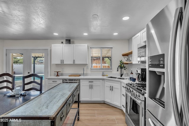 kitchen featuring a textured ceiling, white cabinets, sink, french doors, and stainless steel appliances