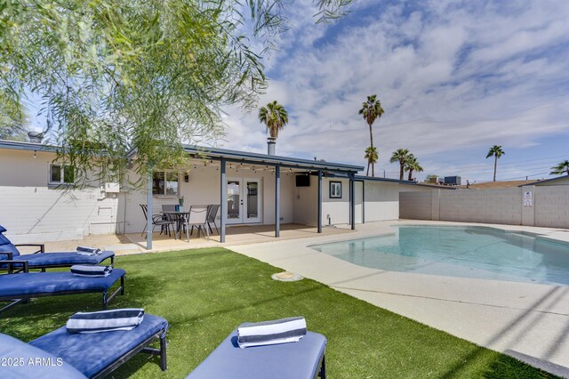 view of swimming pool with a patio area, a lawn, and french doors