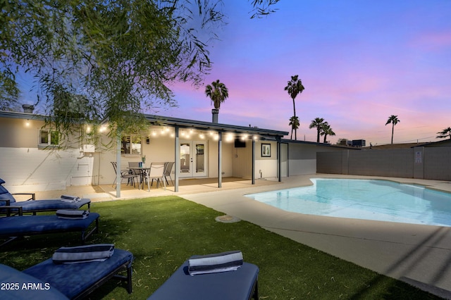 pool at dusk with a patio area, a yard, and french doors