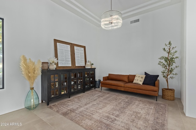 living room with a tray ceiling, an inviting chandelier, and light tile patterned floors