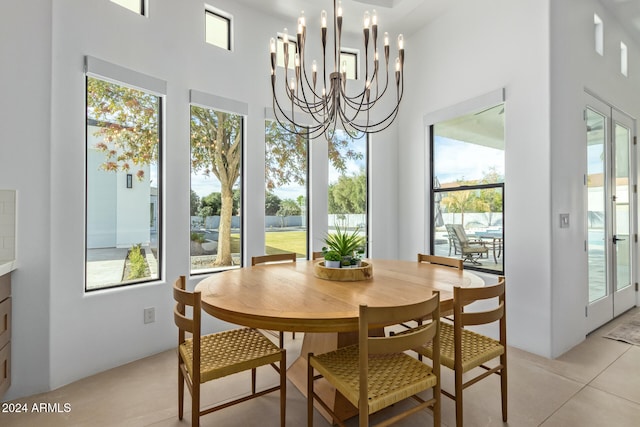 dining room with a towering ceiling, light tile patterned floors, and an inviting chandelier