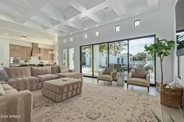 living room with a high ceiling, beamed ceiling, a chandelier, and coffered ceiling