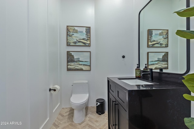 bathroom with toilet, vanity, and parquet floors