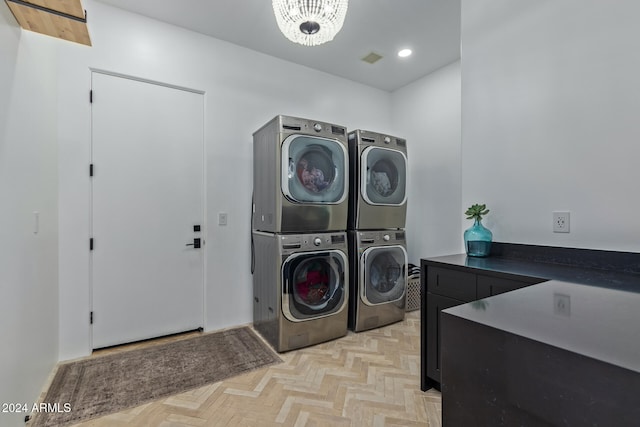 laundry room featuring light parquet flooring, cabinets, stacked washer and clothes dryer, and washing machine and clothes dryer