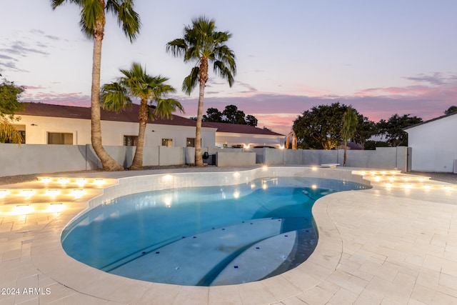 pool at dusk with a patio area