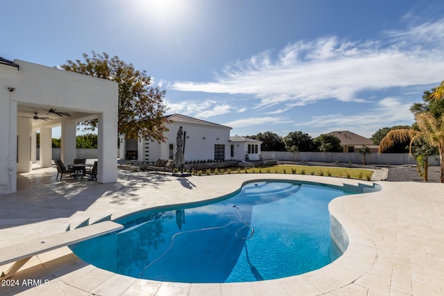 view of swimming pool with a diving board, ceiling fan, and a patio