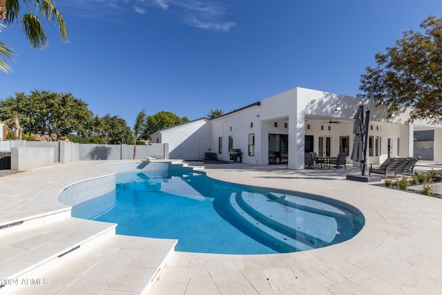 view of swimming pool with ceiling fan, a patio, and a jacuzzi