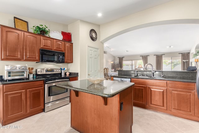 kitchen featuring sink, a kitchen island, a breakfast bar area, stainless steel appliances, and light tile patterned floors