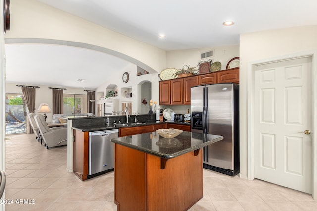 kitchen with sink, a kitchen island, kitchen peninsula, stainless steel appliances, and vaulted ceiling