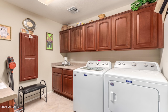 washroom with sink, separate washer and dryer, a textured ceiling, cabinets, and light tile patterned floors