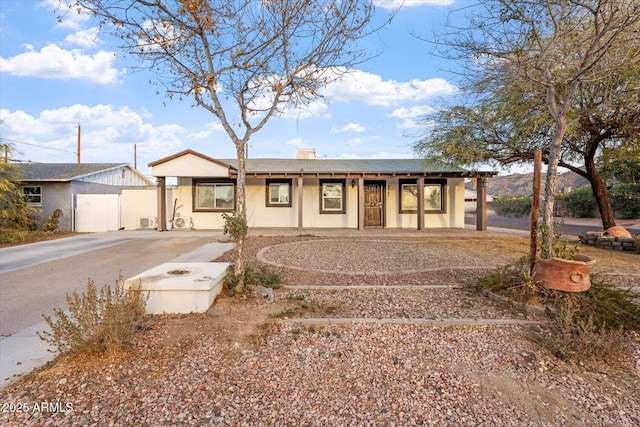 ranch-style home featuring driveway, a chimney, and stucco siding