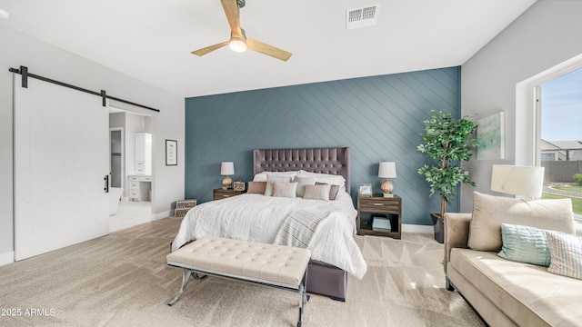 25228 S Star Dr, Queen Creek, AZ 85142 - carpeted bedroom featuring ensuite bathroom, a barn door, visible vents, an accent wall, and a ceiling fan