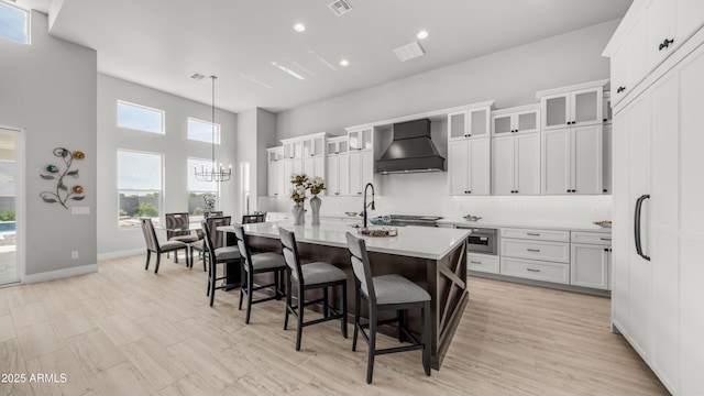 25228 S Star Dr, Queen Creek, AZ 85142 - kitchen featuring a breakfast bar area, premium range hood, a chandelier, light countertops, and a kitchen island with sink
