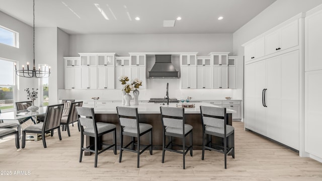 25228 S Star Dr, Queen Creek, AZ 85142 - kitchen with a breakfast bar, a chandelier, wall chimney range hood, light countertops, and an island with sink