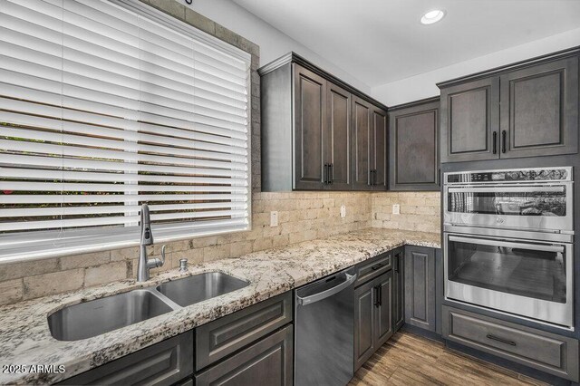 175 E Santa Lucia Ln, Queen Creek, AZ 85140 - kitchen featuring appliances with stainless steel finishes, light stone counters, a sink, wood finished floors, and decorative backsplash