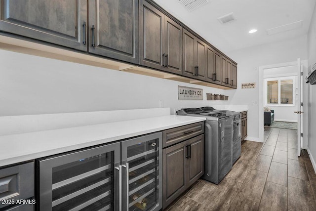 175 E Santa Lucia Ln, Queen Creek, AZ 85140 - laundry area with dark wood-style flooring, visible vents, washer and clothes dryer, cabinet space, and beverage cooler