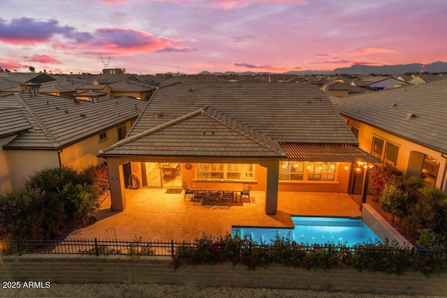 175 E Santa Lucia Ln, Queen Creek, AZ 85140 - back of property at dusk with a tiled roof, a patio area, fence, stucco siding, and a fenced in pool