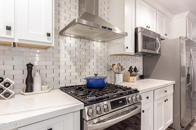 kitchen featuring white cabinetry, light stone counters, stainless steel appliances, decorative backsplash, and wall chimney range hood