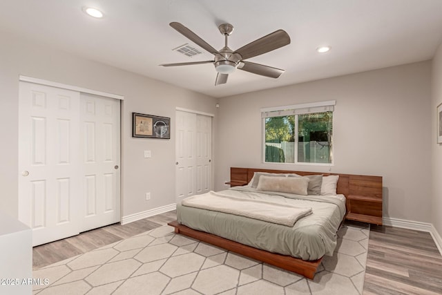 bedroom featuring ceiling fan, multiple closets, and light wood-type flooring